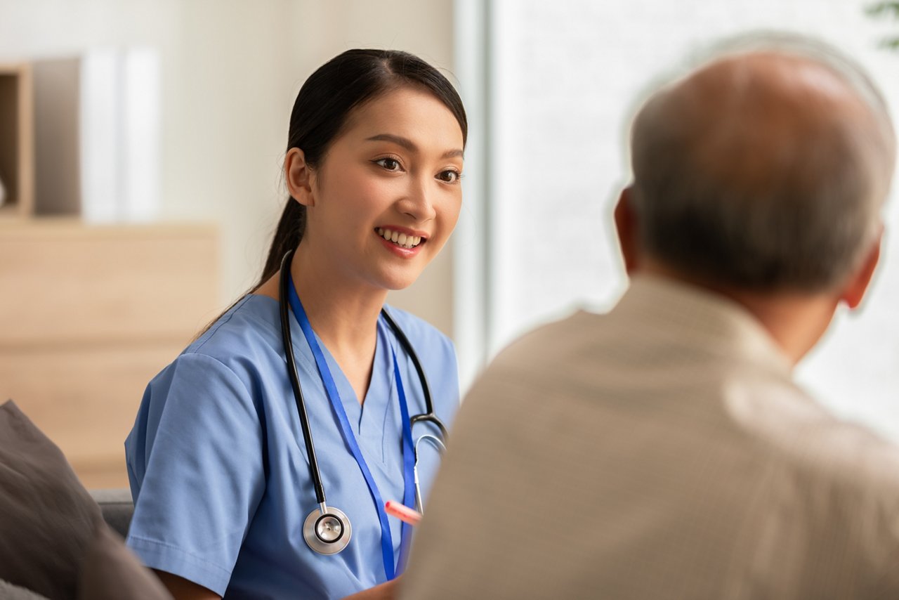 Nurse with stethoscope talks to a senior-aged man