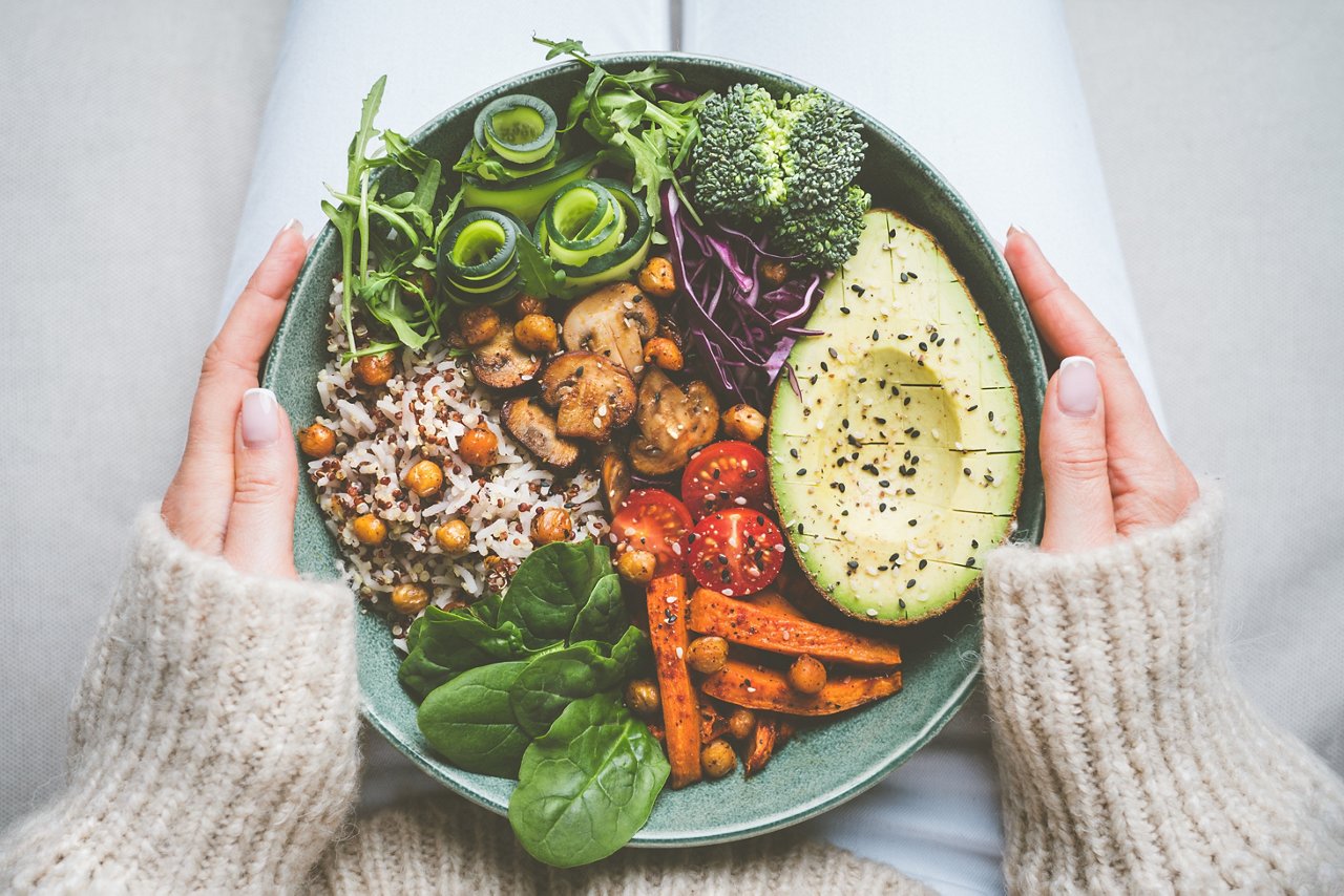 Woman holds a plate of vegetable salad.