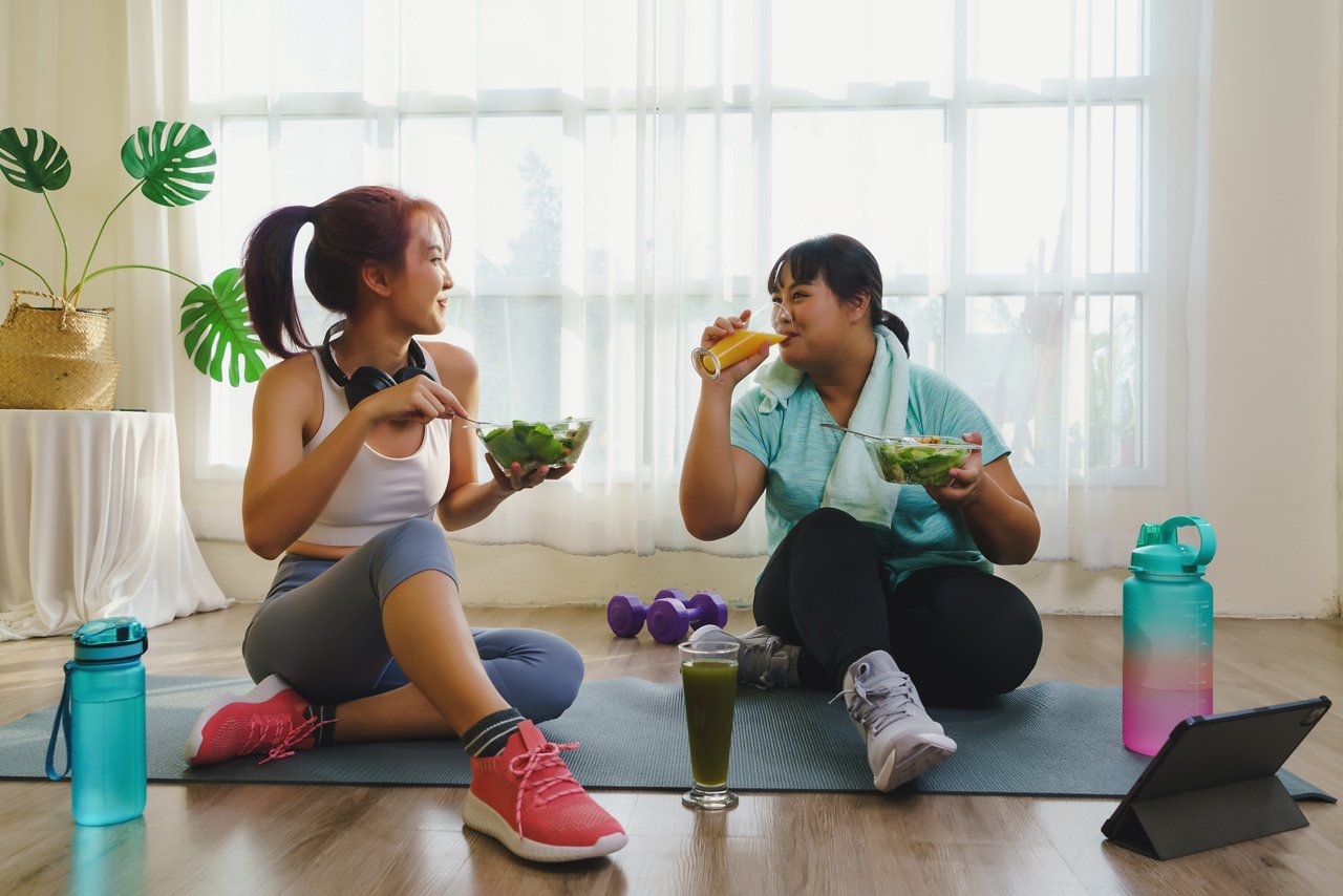 Two female friends eat after a fitness workout.