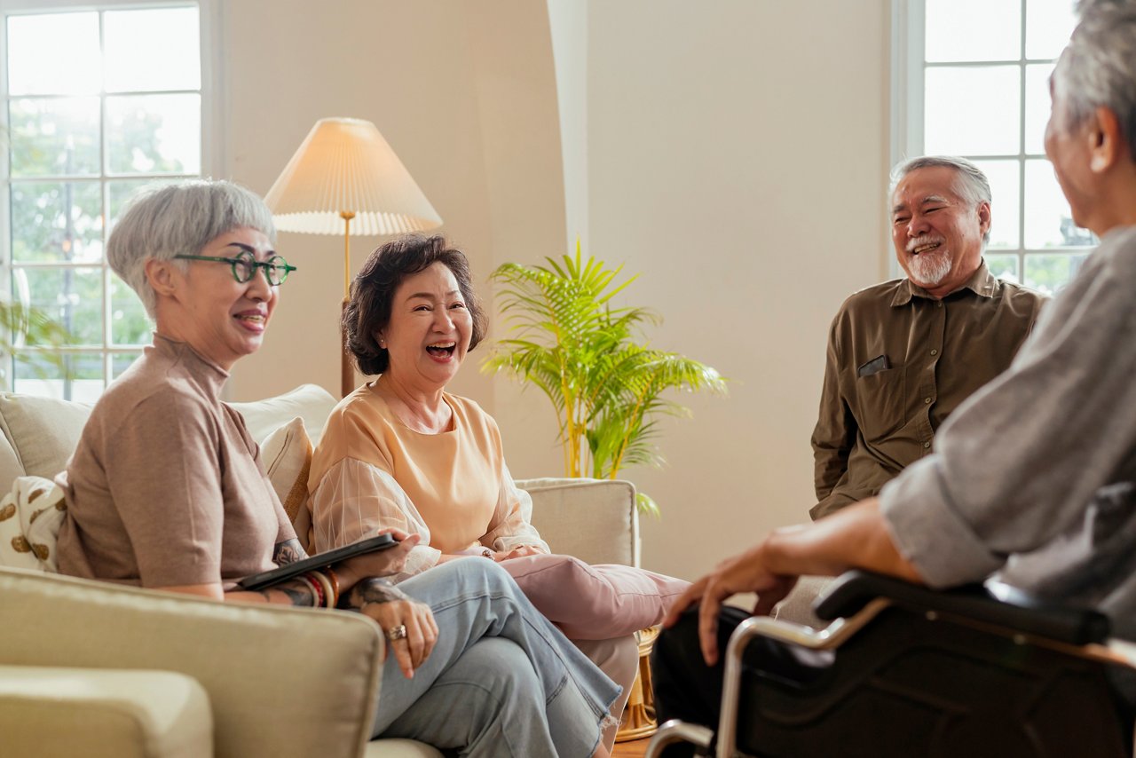 A mix of male and female senior citizens laugh and talk.