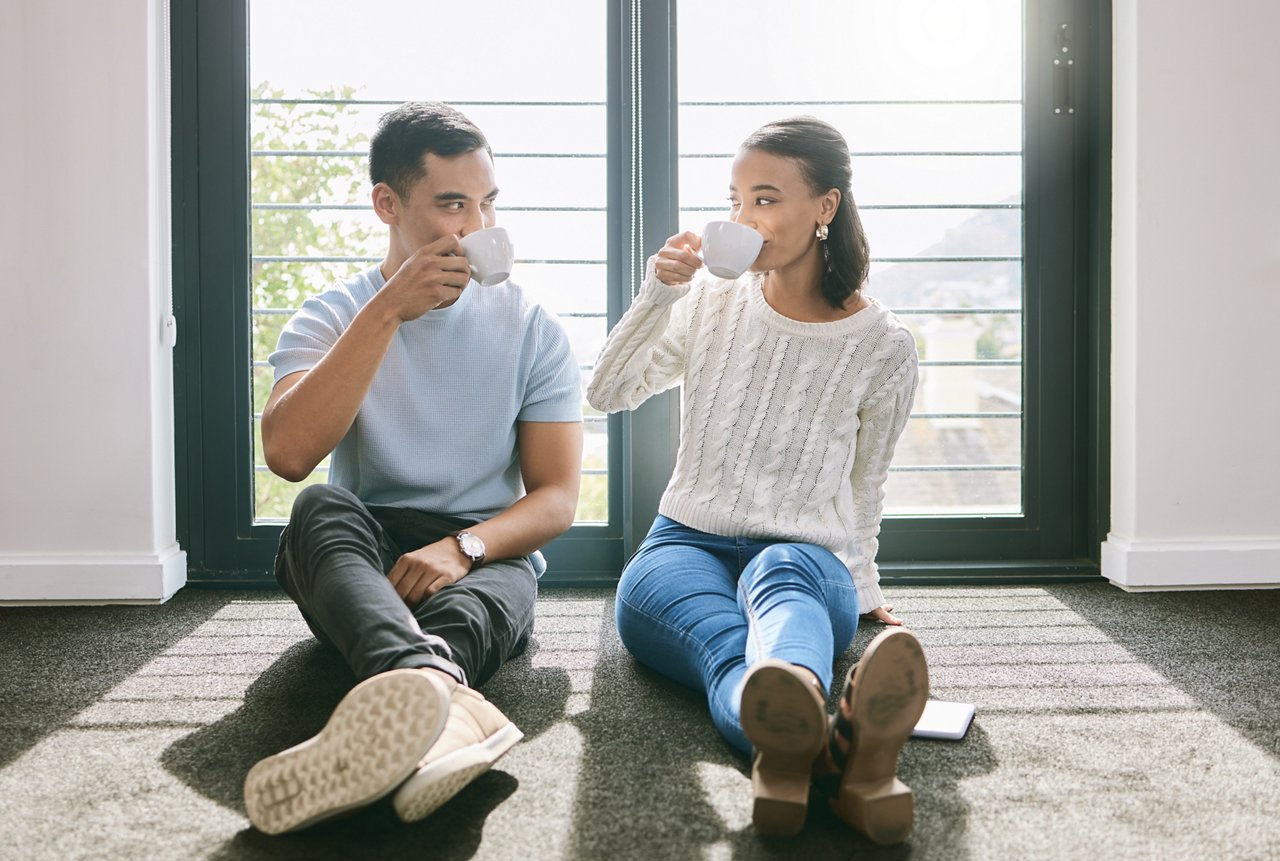 Young couple sips tea while relaxing on the floor.