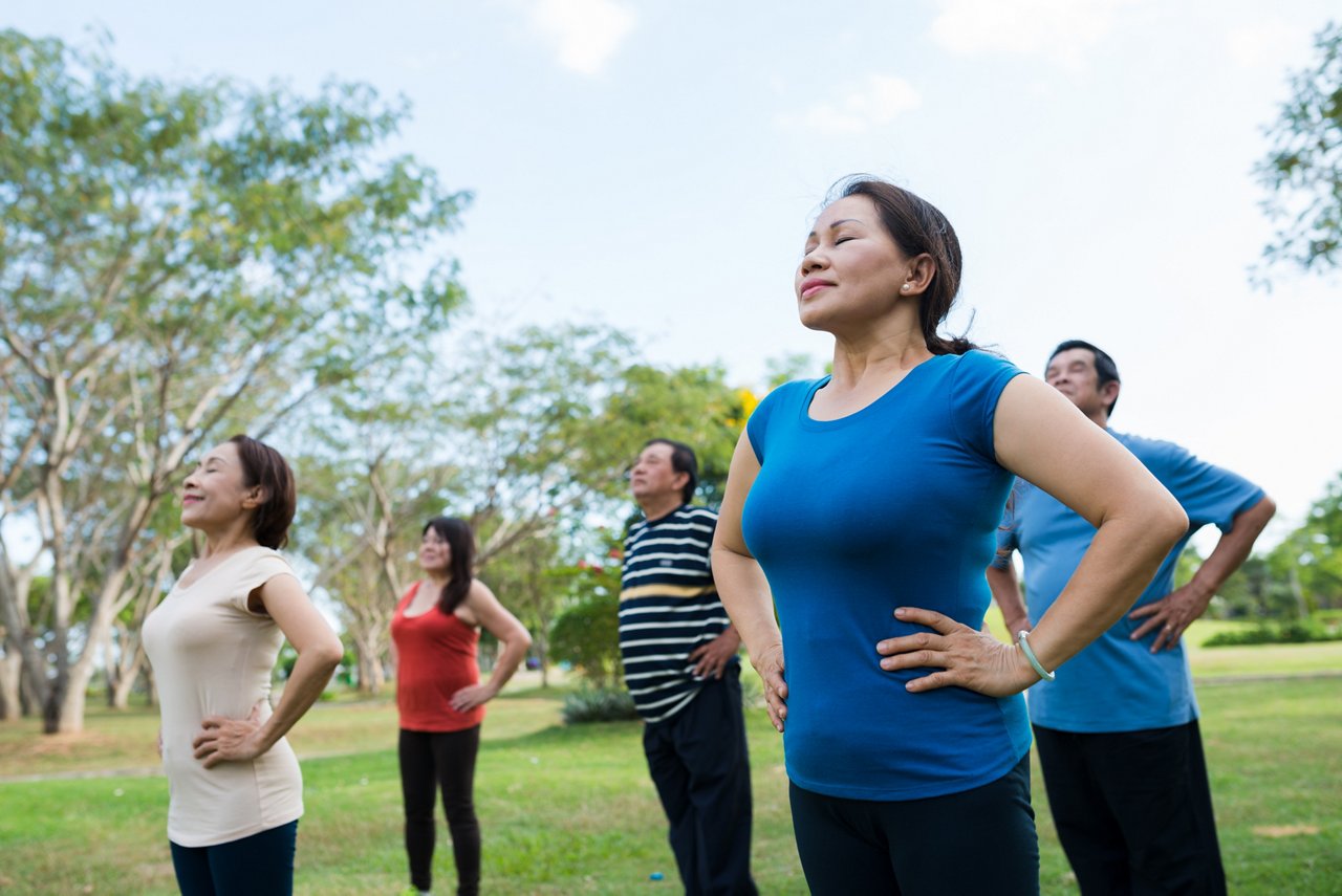 A group of seniors practice breathing exercises outdoor