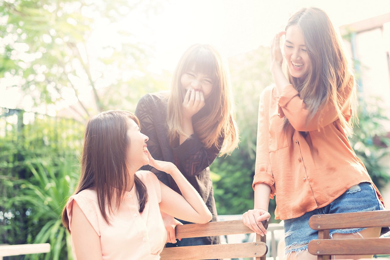 三位年輕的亞裔女性在一起嬉笑玩耍，看起來很開心 