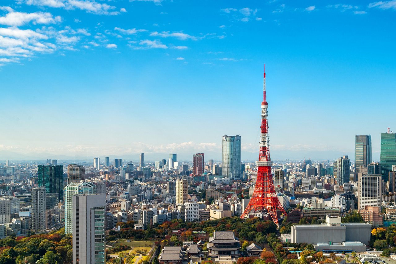 The Tokyo Tower of Japan surrounded by buildings against a blue-sky backdrop
