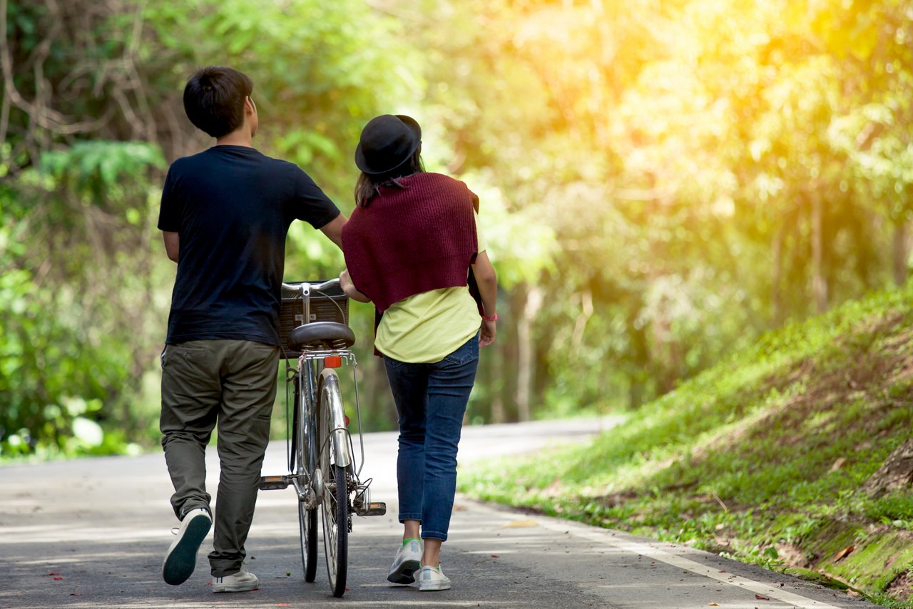 Young couple walk beside their bike at a nature trail