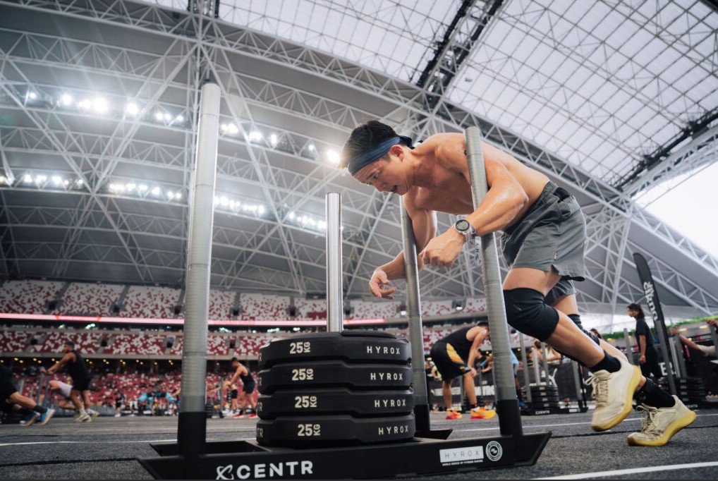 Participant performing a sled push at a HYROX training station.