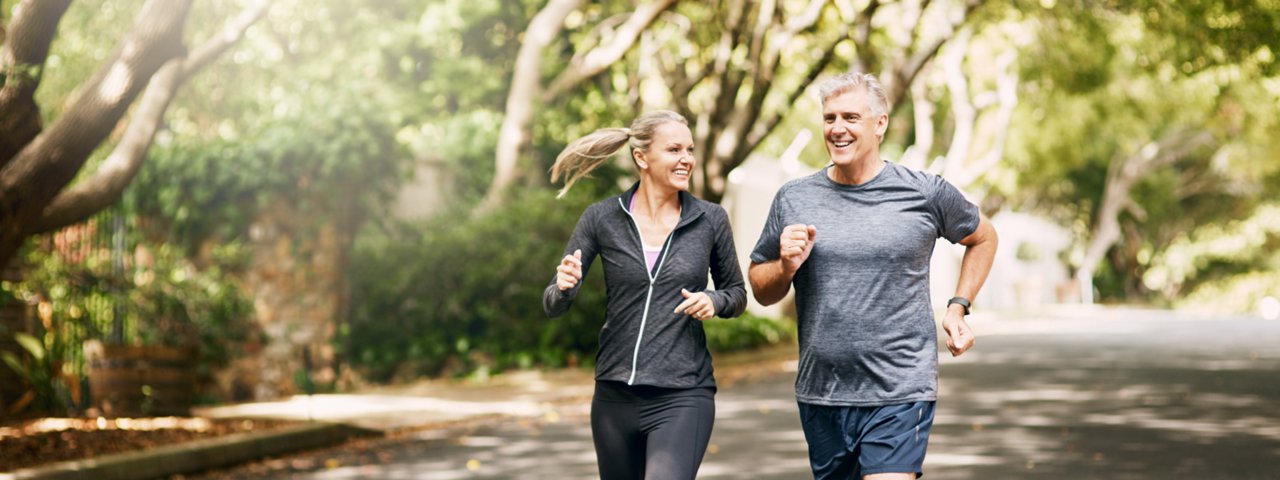 A man and woman jogging together on a scenic road, showcasing an active lifestyle and outdoor fitness.