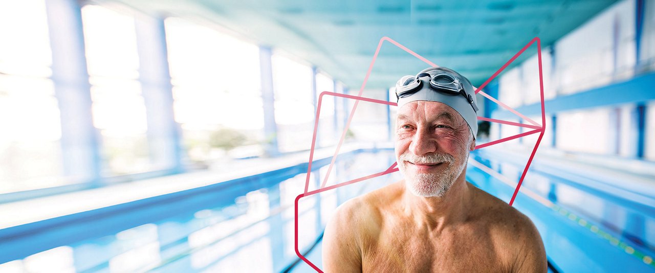 An older man wearing a swim cap and goggles, preparing for a swim