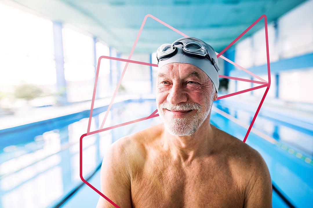 An older man wearing a swim cap and goggles, preparing for a swim