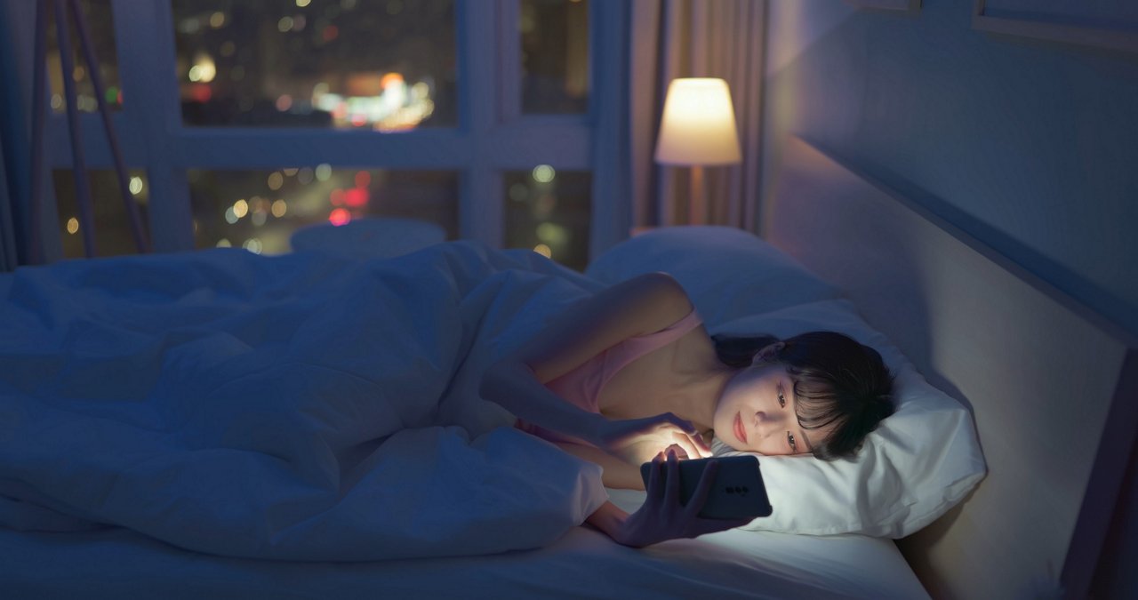 年輕女性睡覺前躺在床上玩手機