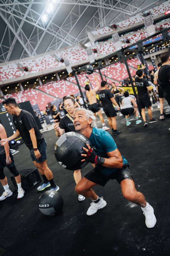 Hyrox participant squatting and throwing a medicine ball against the wall