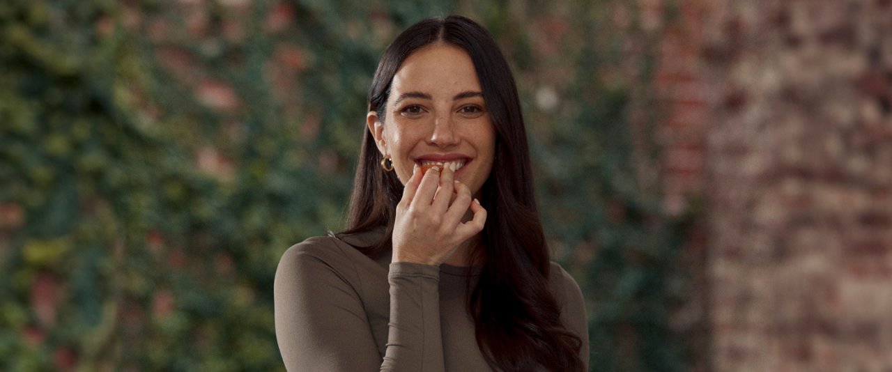 Marika Day, AIA Ambassador, smiles at the camera while holding a delicious piece of food