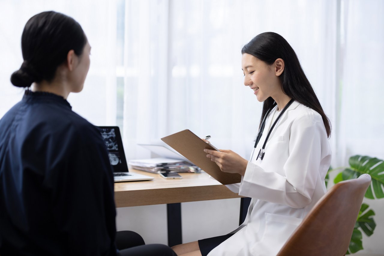 A young adult discussing health screening results with a healthcare professional in a clinic, representing early-onset cancer awareness, cancer screening, and the importance of early detection.