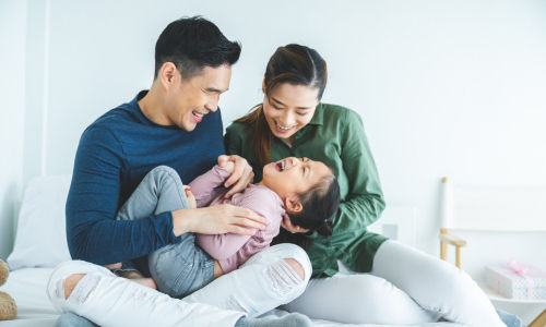 Happy Asian family playing on the bed.