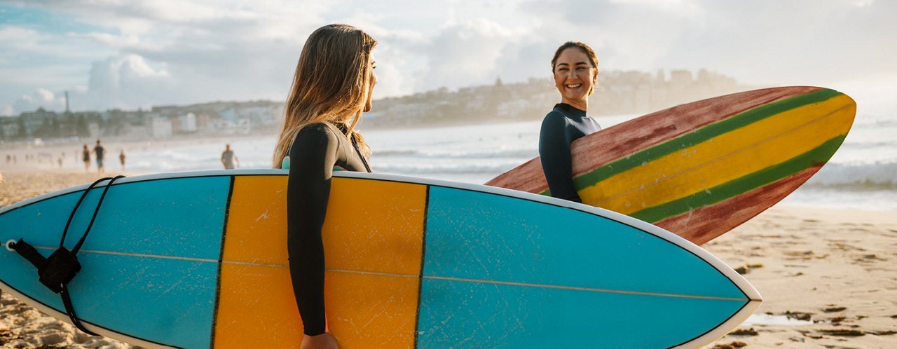 2 women holding surfing board