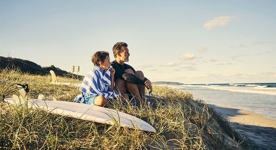 a man and a kid sitting on a mountain top