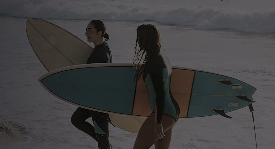 two girls holding surfing pads
