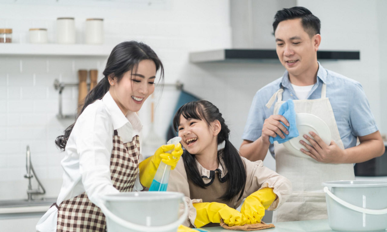 Asian parents and their daughter clean the kitchen counter together