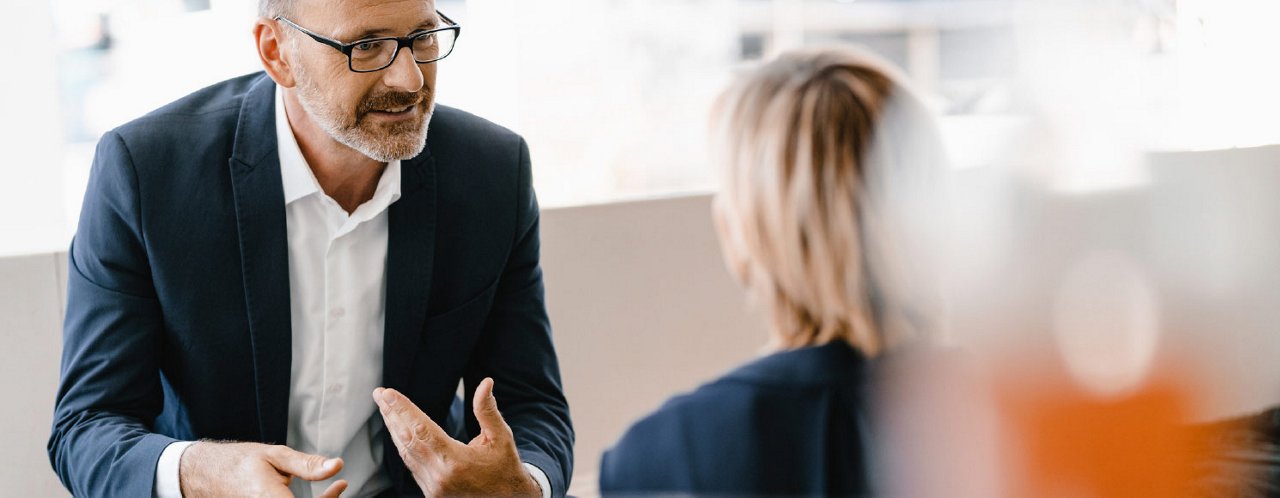 man in suits taking to a lady at office