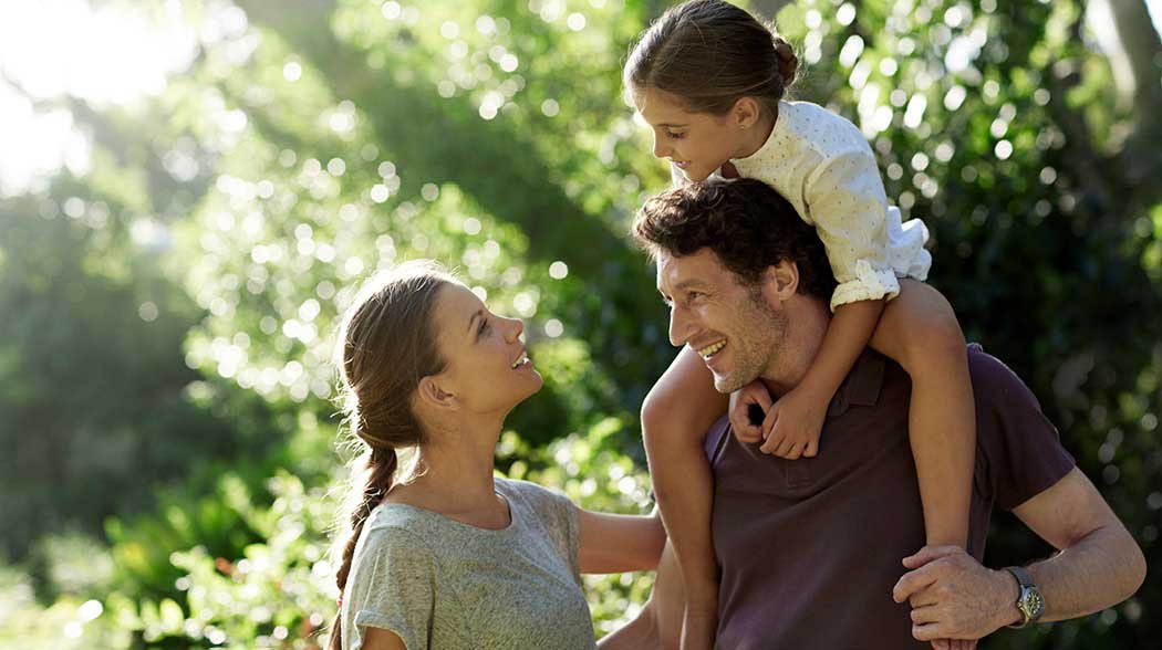 a man holding child over his shoulders and talking to a woman