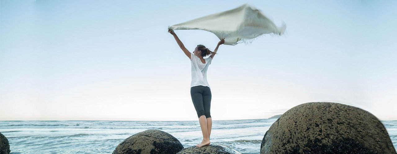 a woman standing on a rock near sea