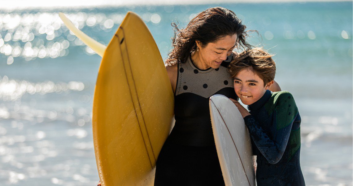 Mother and daughter at the beach with surfboards
