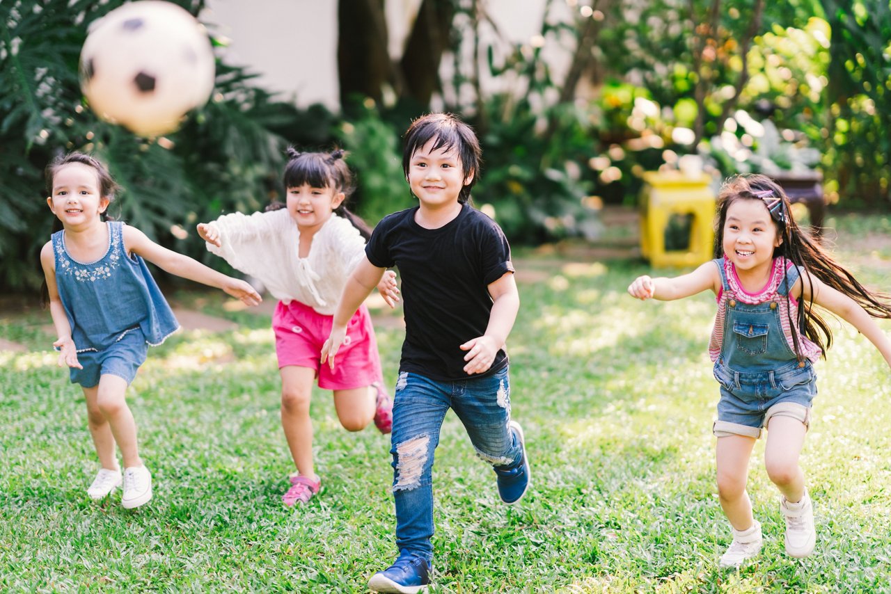 Boys and girls playing soccer on the grass, in a garden