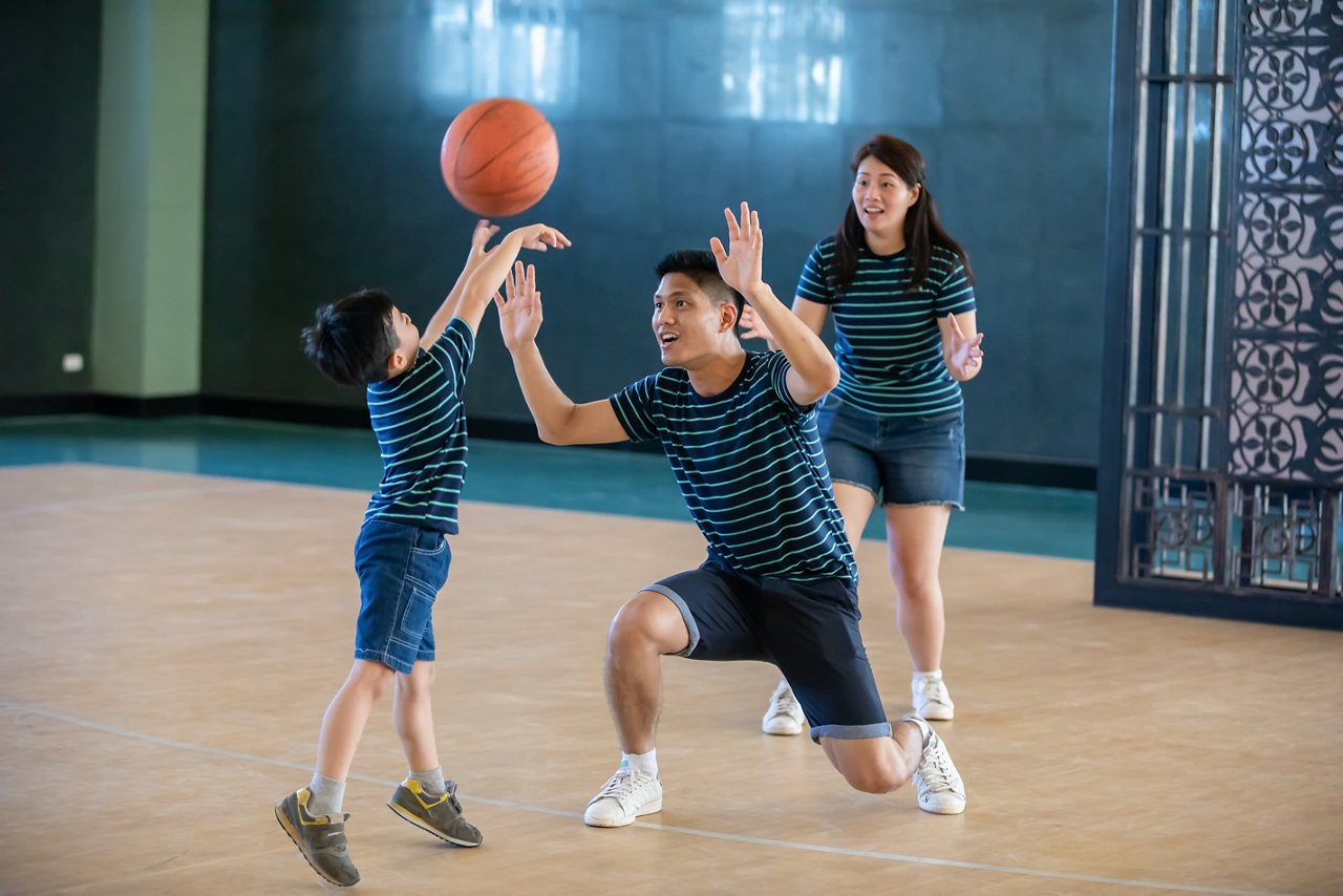 Asian dad and mom teaching their son to play basketball