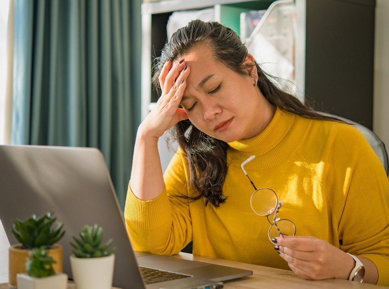 A middle-aged woman has her hand on her forehead like she has a headache