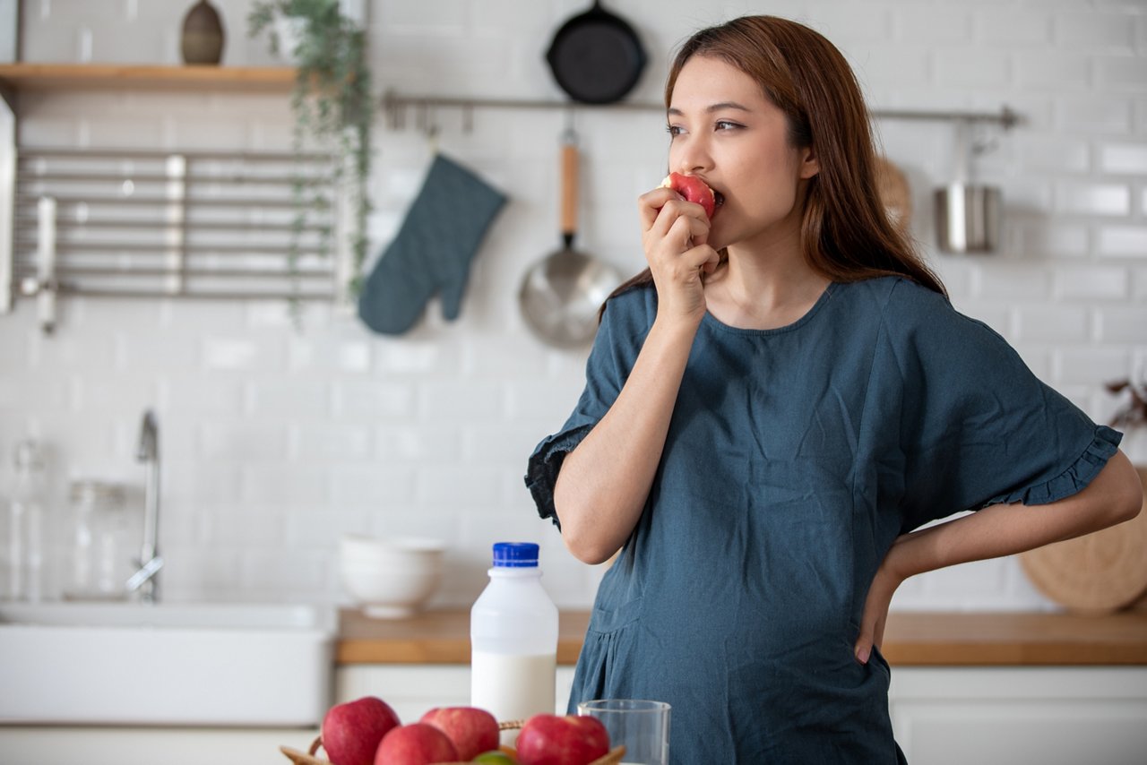 Pregnant woman eats an apple