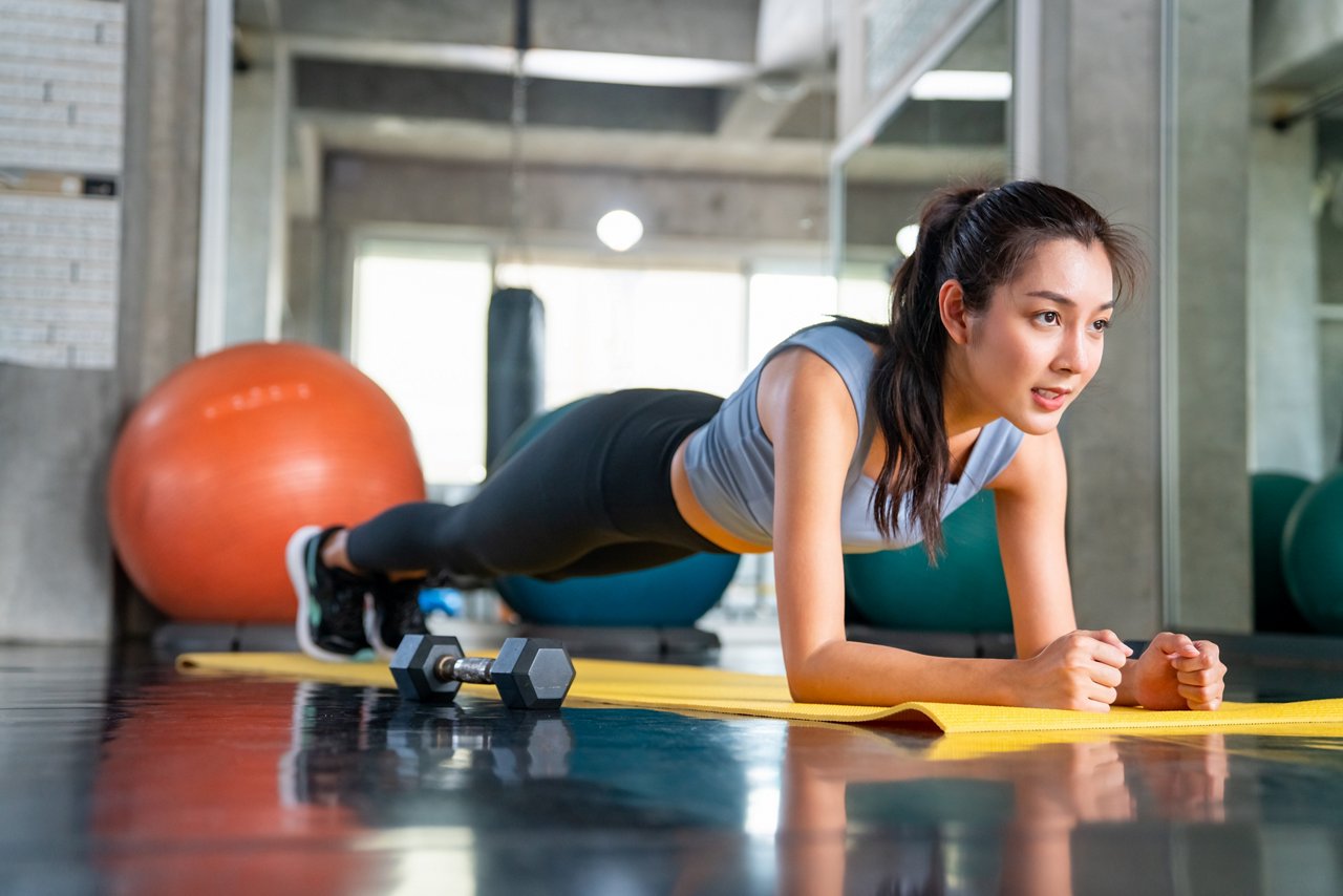 Two women and a man doing weight training using small dumbbells 