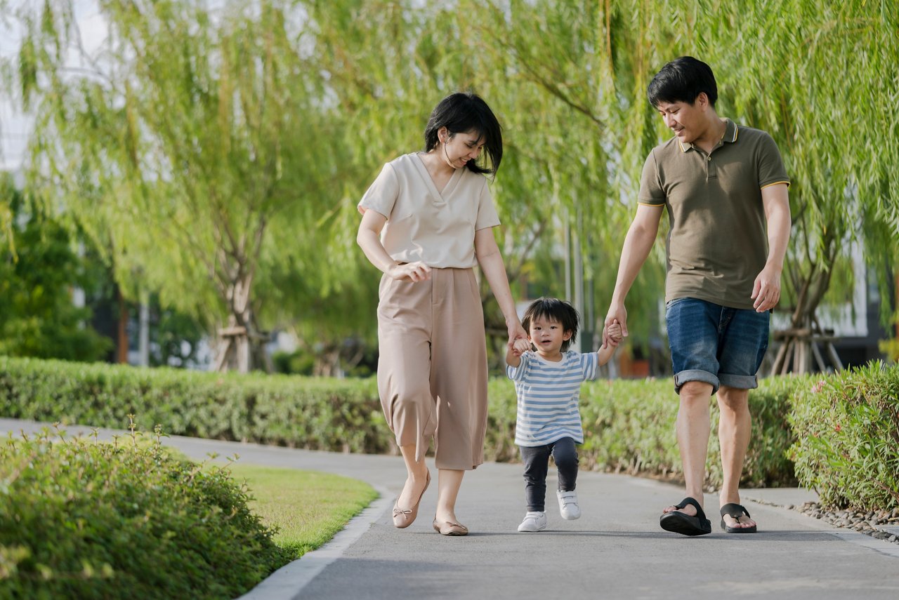 A family of three walking hand in hand in the park