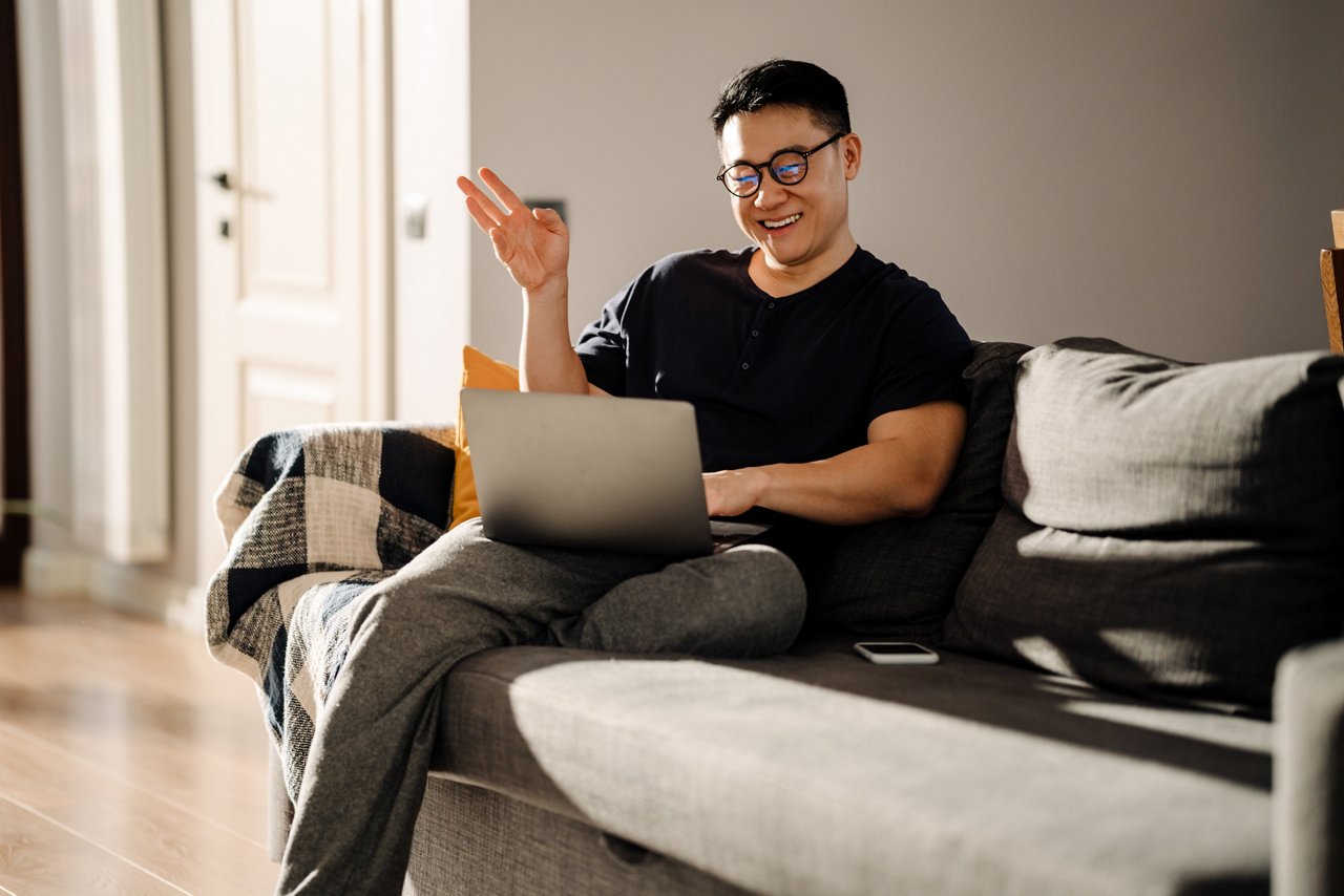 A man with glasses working on his laptop at home