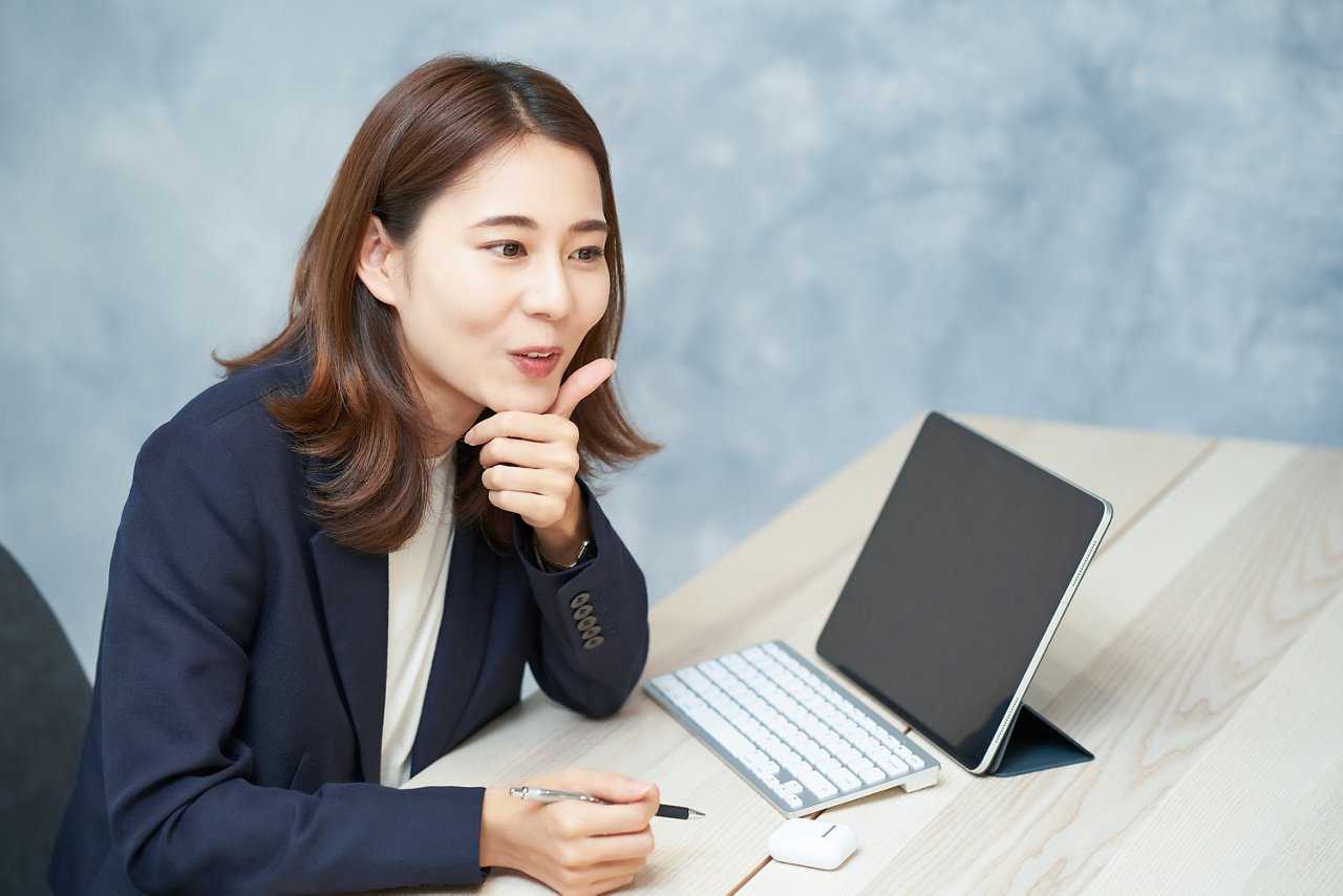 A woman talking to someone off camera, an open laptop on her des