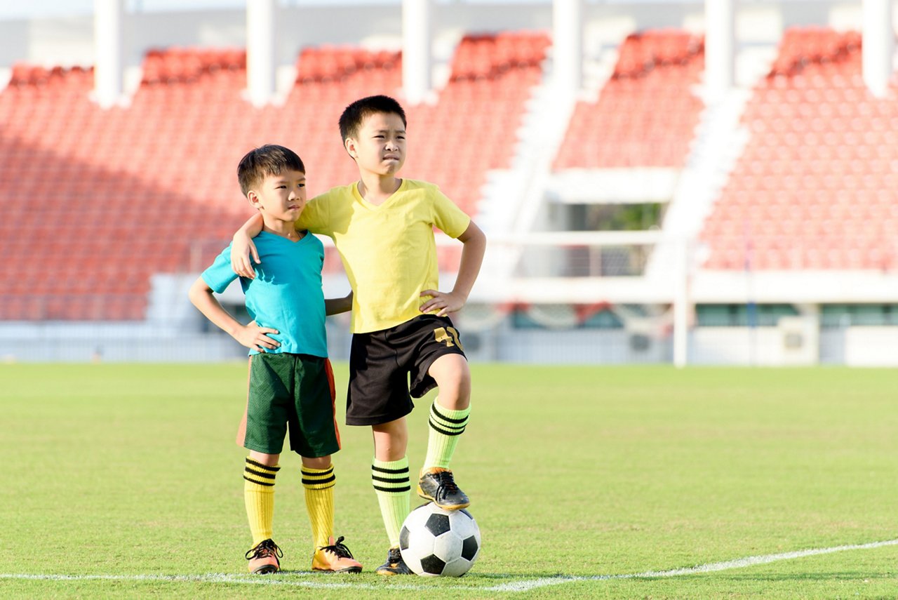 Two boys in soccer uniforms stand tall in a stadium