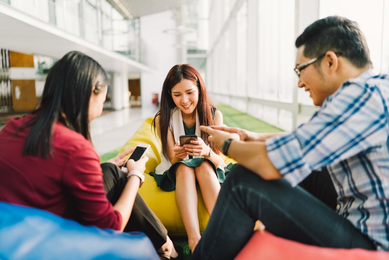  A group of two women and one man using their phones 