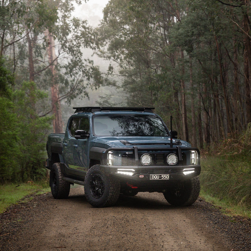 Blue Kia Tasman on a rural road.