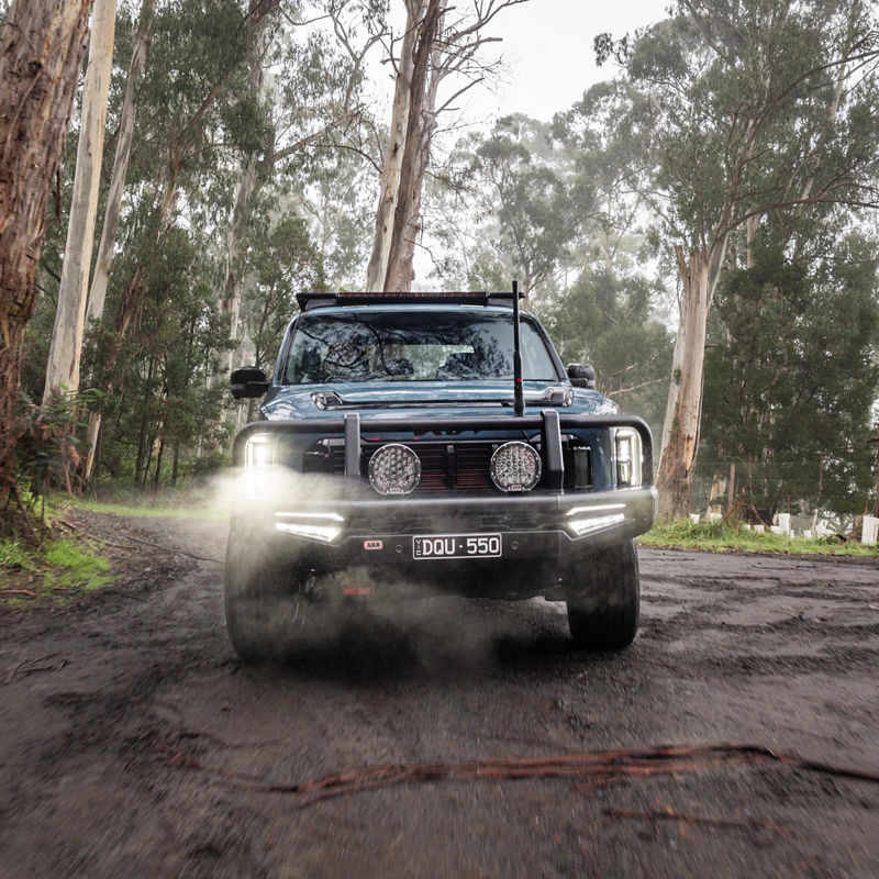 Kia Tasman in a road in the woods.