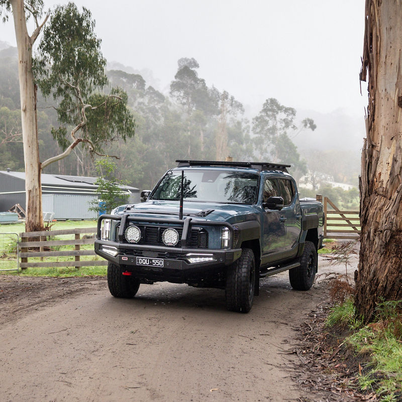 Kia Tasman in a rural road.