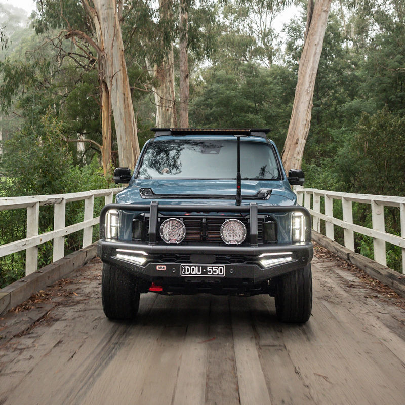 Blue Kia Tasman crossing a bridge.