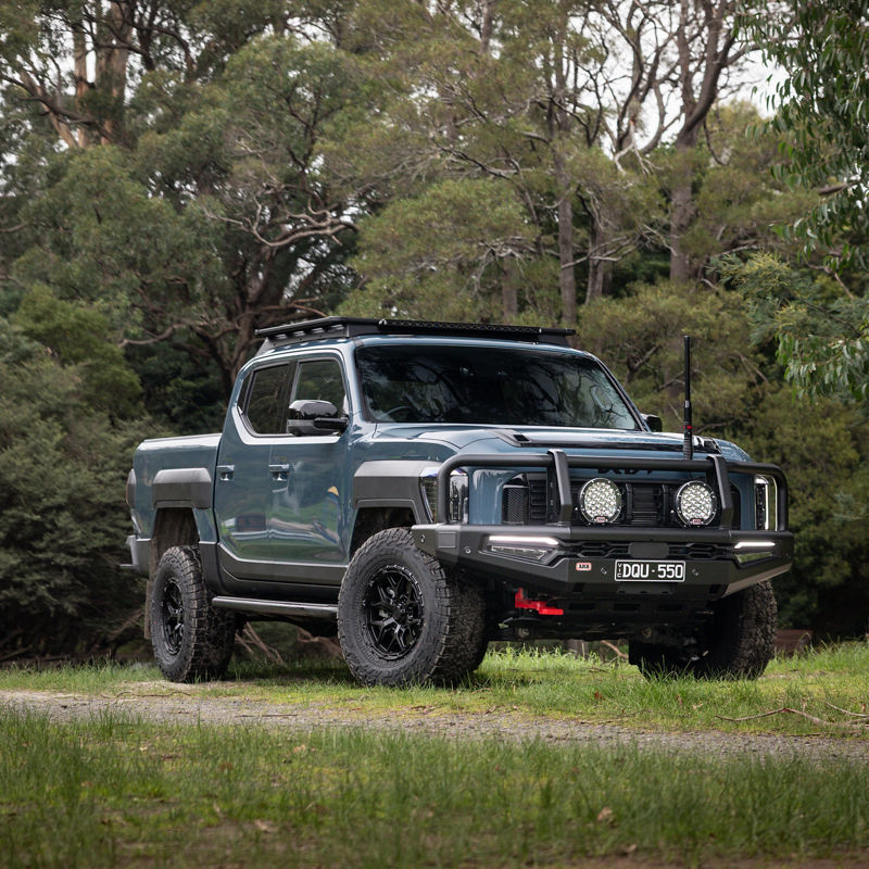 Blue Kia Tasman in a rural area.