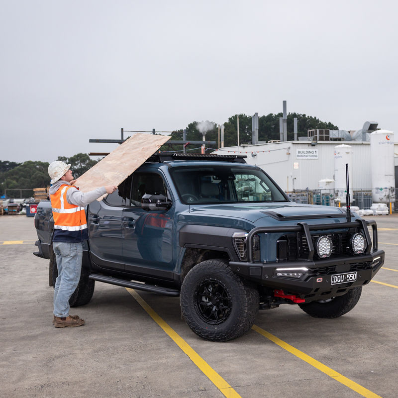 Construction worker loading up a blue Kia Tasman.