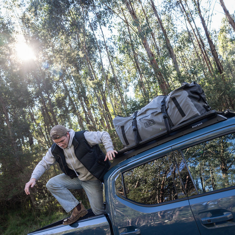 Young man climbing out the back of a blue Kia Tasman.