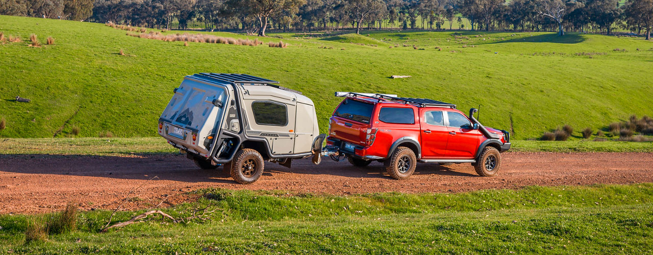 Isuzu D-Max towing an ARB Earth Camper on a rural road.
