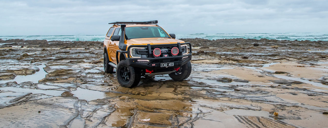 ARB equipped Ford Ranger on a rocky coastal shoreline with an ARB bull bar and driving lights.