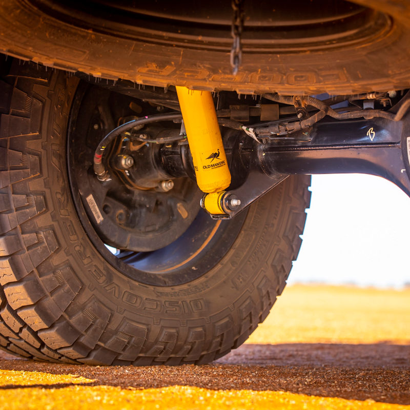 Close-up view of a Ford Ranger PXIII rear suspension showing an ARB Old Man Emu shock absorber, rear axle and all-terrain tyre on sandy terrain.