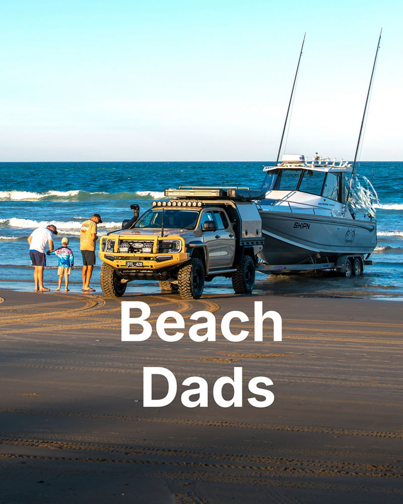 Father and child on a beach beside an ARB-equipped ute towing a boat into the water.