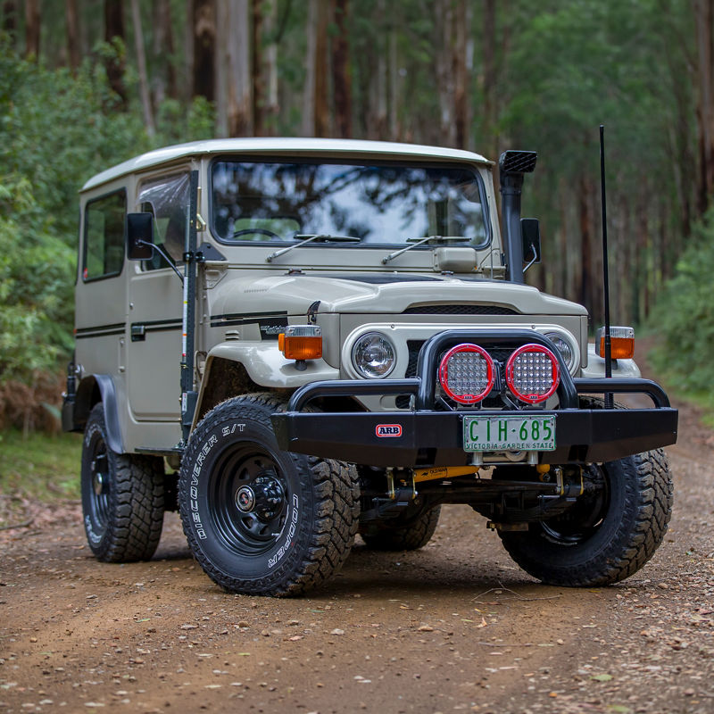 Toyota LandCruiser 40 Series fitted with an ARB bull bar, Intensity driving lights and snorkel, parked on a forest track.