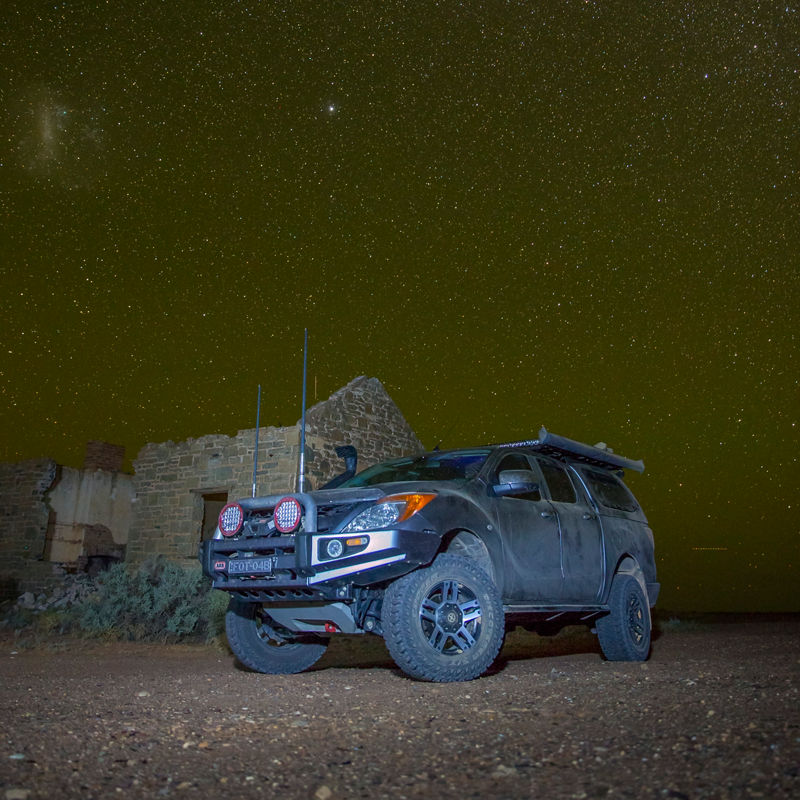 ARB equipped Mazda BT-50 parked beside a historic stone building under a star filled night sky.