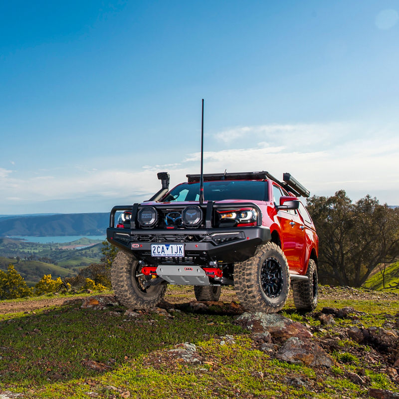 ARB equipped Mazda BT-50 fitted with a bull bar, driving lights, canopy and roof rack system parked on a rocky ridgeline overlooking a mountain landscape.